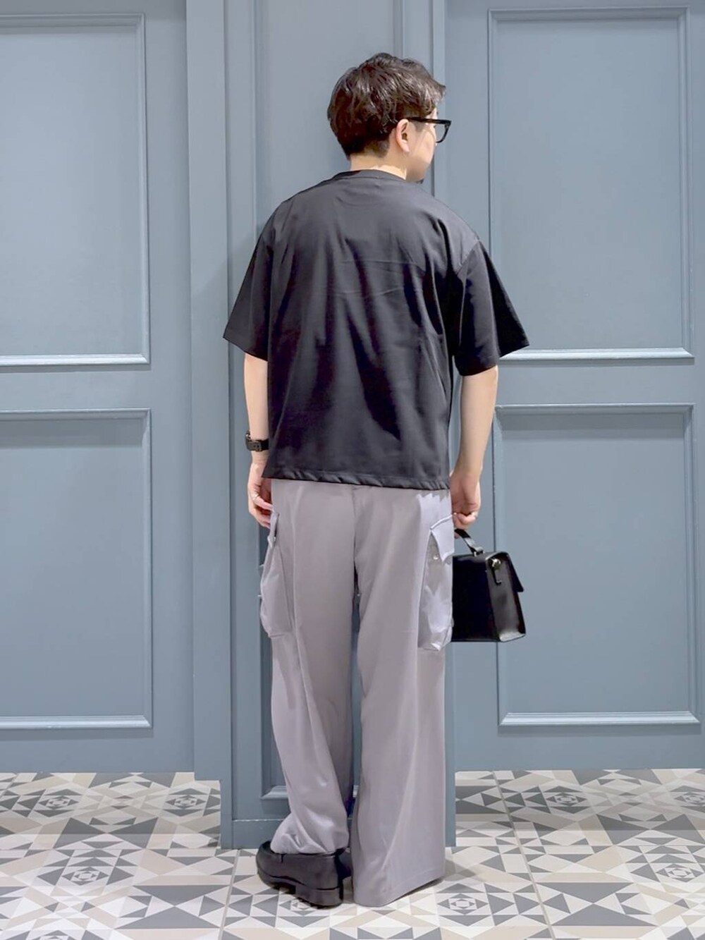 ブラック系のTシャツ/カットソー、ブラック系のローファー、ブラック系のショルダーバッグを着用したメンズの秋コーディネートの3枚目の写真