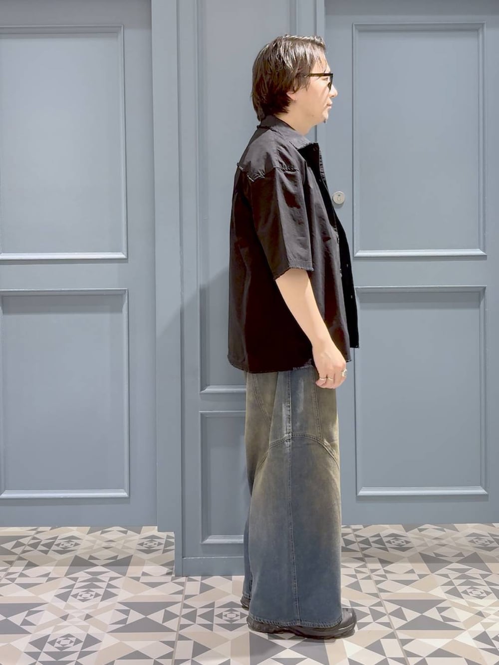 ブラック系のシャツ/ブラウス、ブラック系のスニーカー、ブルー系のデニムパンツを着用したメンズの夏コーディネートの2枚目の写真