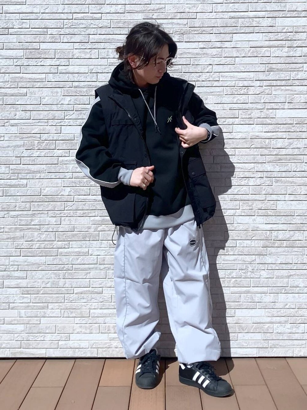 ブラック系のパーカー、ブラック系のナイロンジャケット、ホワイト系のスウェットパンツを着用したメンズの春コーディネートの4枚目の写真