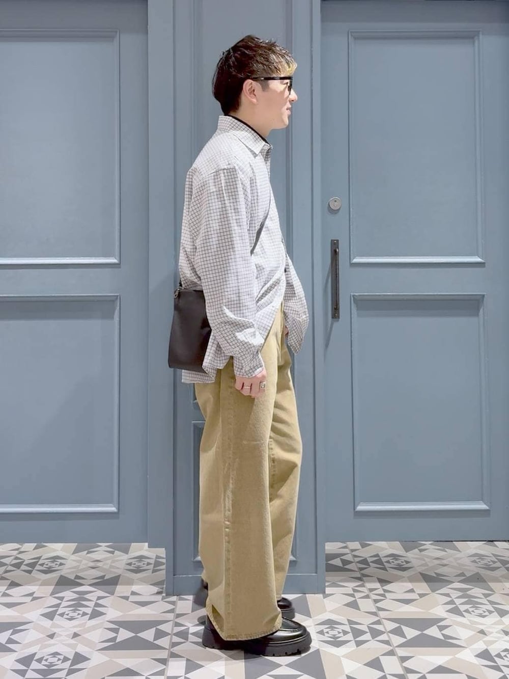 ベージュ系のデニムパンツ、ブラック系のショルダーバッグ、ブラック系のドレスシューズを着用したメンズの冬コーディネートの2枚目の写真