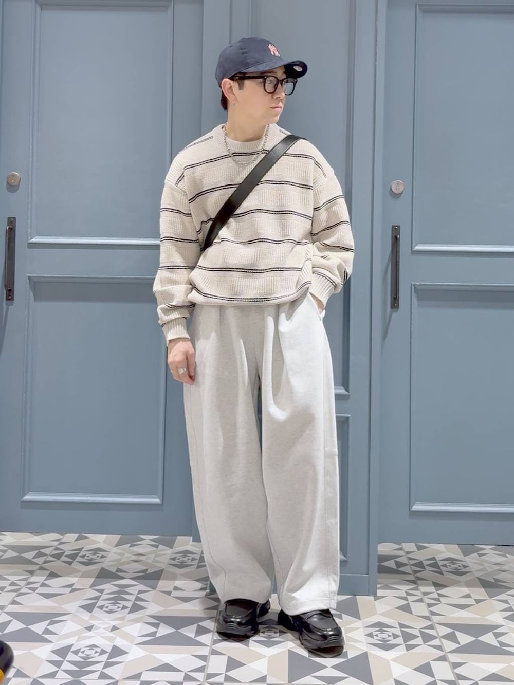 ブラック系のローファー、ブラック系のショルダーバッグ、グレー系のスウェットパンツを着用したメンズの冬コーディネートの4枚目の写真