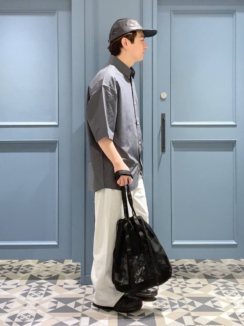 ブラック系のスニーカー、グレー系のシャツ/ブラウス、ブラック系のトートバッグを着用したメンズの春コーディネートの2枚目の写真