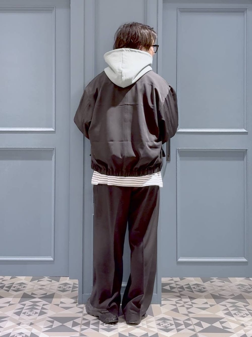 ブラック系のスニーカー、ブラック系のスラックス、グリーン系のパーカーを着用したメンズの春コーディネートの3枚目の写真