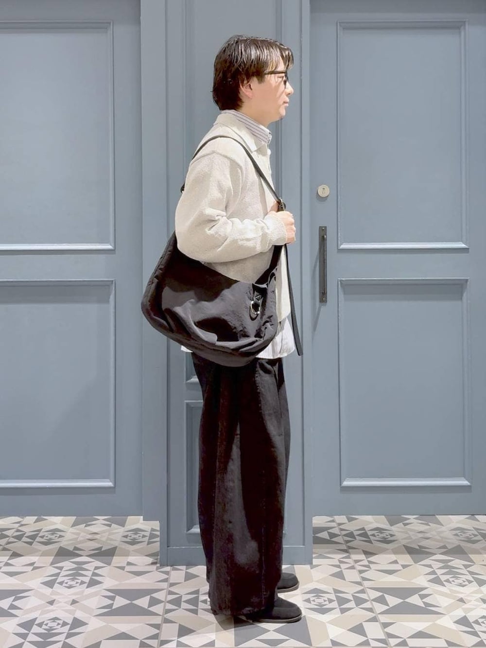 ブラック系のショルダーバッグ、ホワイト系のシャツ/ブラウス、ブラック系のデニムパンツを着用したメンズの春コーディネートの2枚目の写真