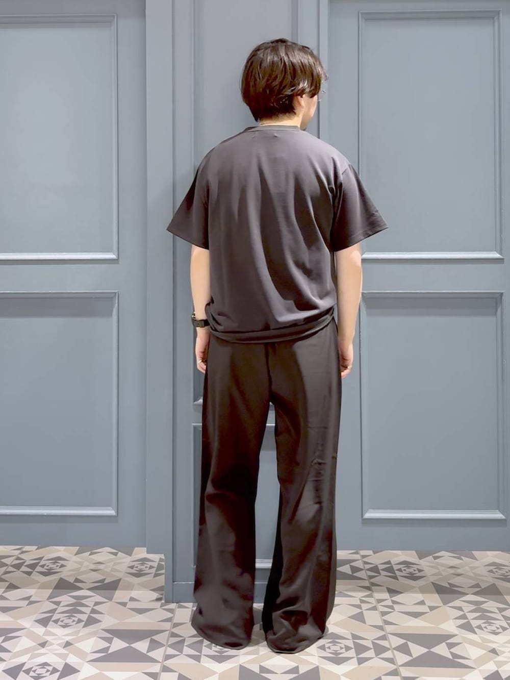 ブラック系のローファー、グレー系のスラックス、ブラック系のTシャツ/カットソーを着用したメンズの夏コーディネートの3枚目の写真