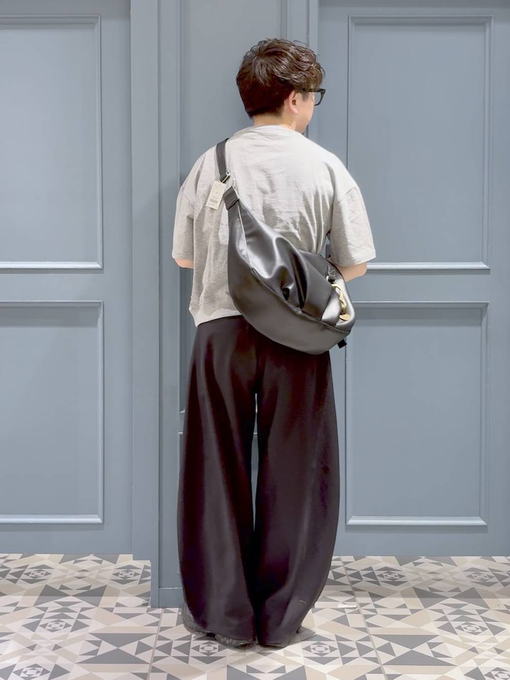 ブラック系のスラックス、ブラック系のスニーカー、ブラック系のショルダーバッグを着用したメンズの春コーディネートの3枚目の写真