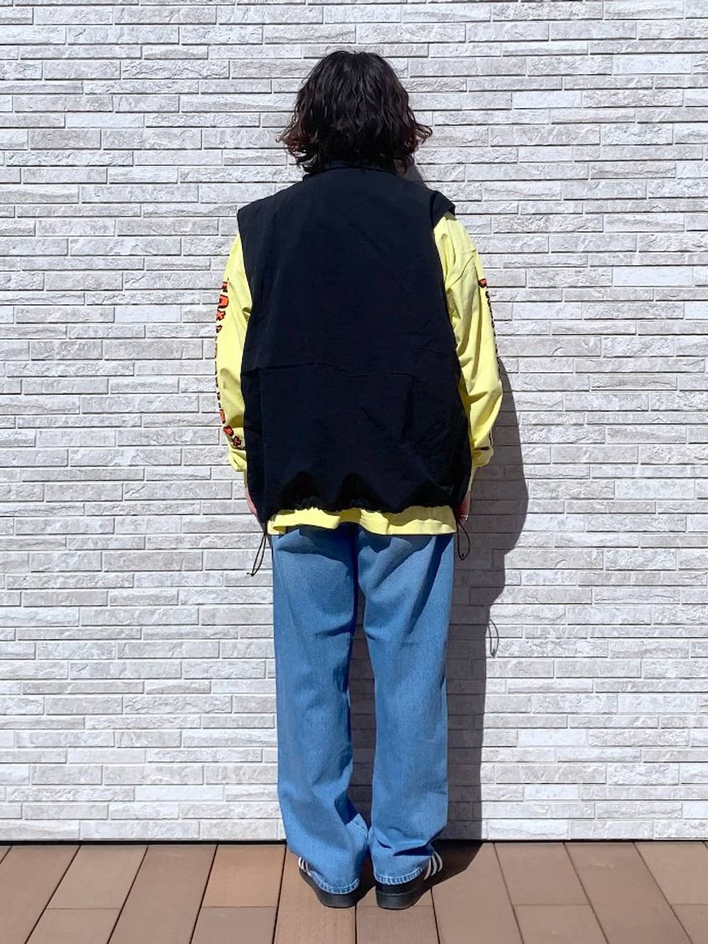 イエロー系のTシャツ/カットソー、ブルー系のデニムパンツ、ブラック系のナイロンジャケットを着用したメンズの春コーディネートの3枚目の写真