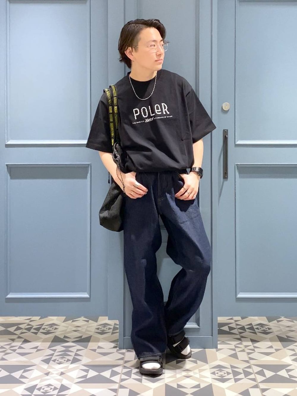 ブルー系のデニムパンツ、ブラック系のサンダル、ブラック系のトートバッグを着用したメンズの春コーディネートの4枚目の写真