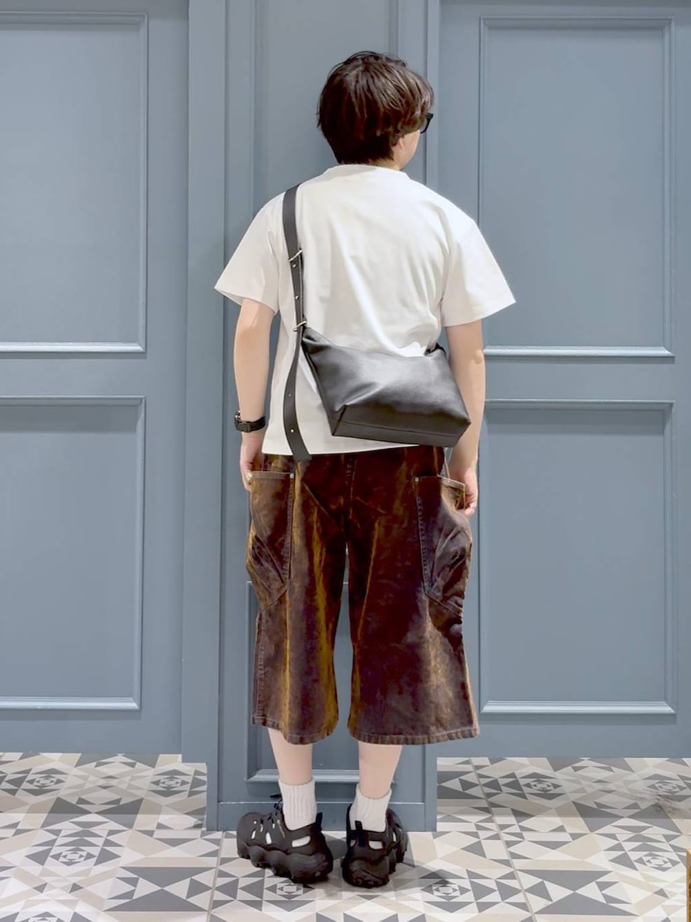 ブラック系のサンダル、ブラック系のショルダーバッグ、ホワイト系のTシャツ/カットソーを着用したメンズの夏コーディネートの3枚目の写真