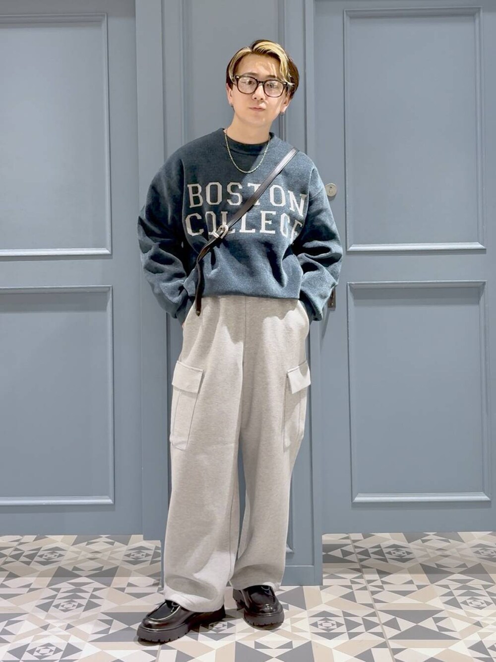 グリーン系のニット/セーター、ブラック系のドレスシューズ、グレー系のスウェットパンツを着用したメンズの秋コーディネートの4枚目の写真