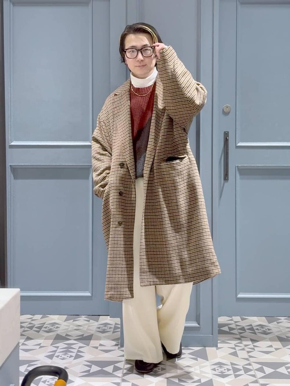 ブラウン系のチェスターコート、レッド系のニット/セーター、ホワイト系のスラックスを着用したメンズの冬コーディネートの4枚目の写真