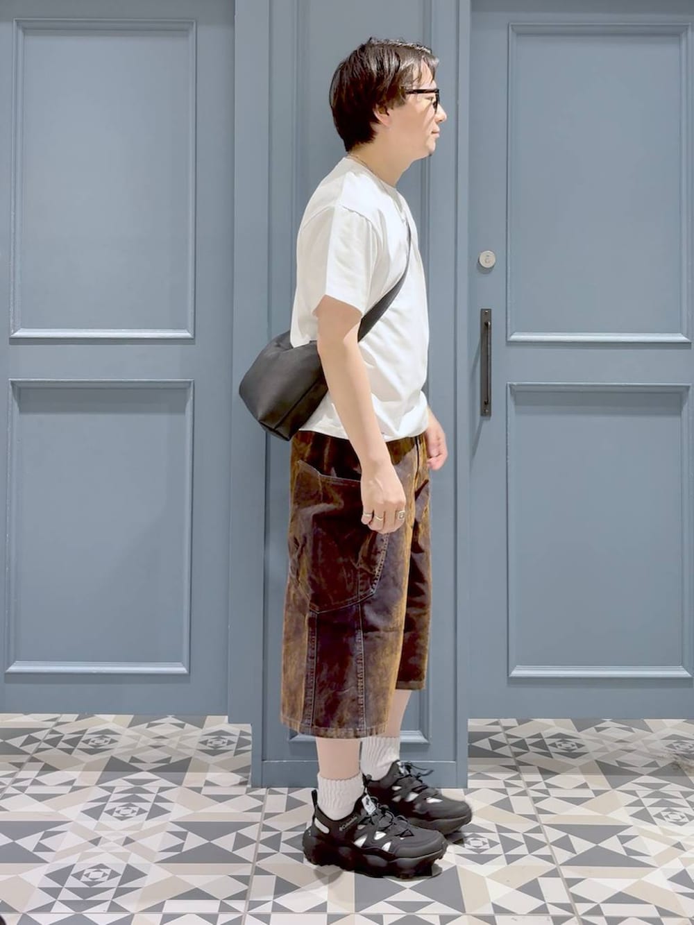 ブラック系のサンダル、ブラック系のショルダーバッグ、ホワイト系のTシャツ/カットソーを着用したメンズの夏コーディネートの2枚目の写真