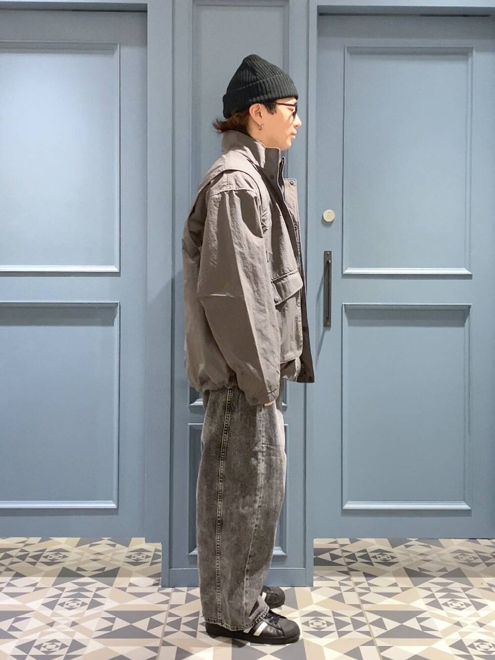 グレー系のデニムパンツ、グレー系のブルゾン、ブルー系のニット/セーターを着用したメンズの秋コーディネートの2枚目の写真