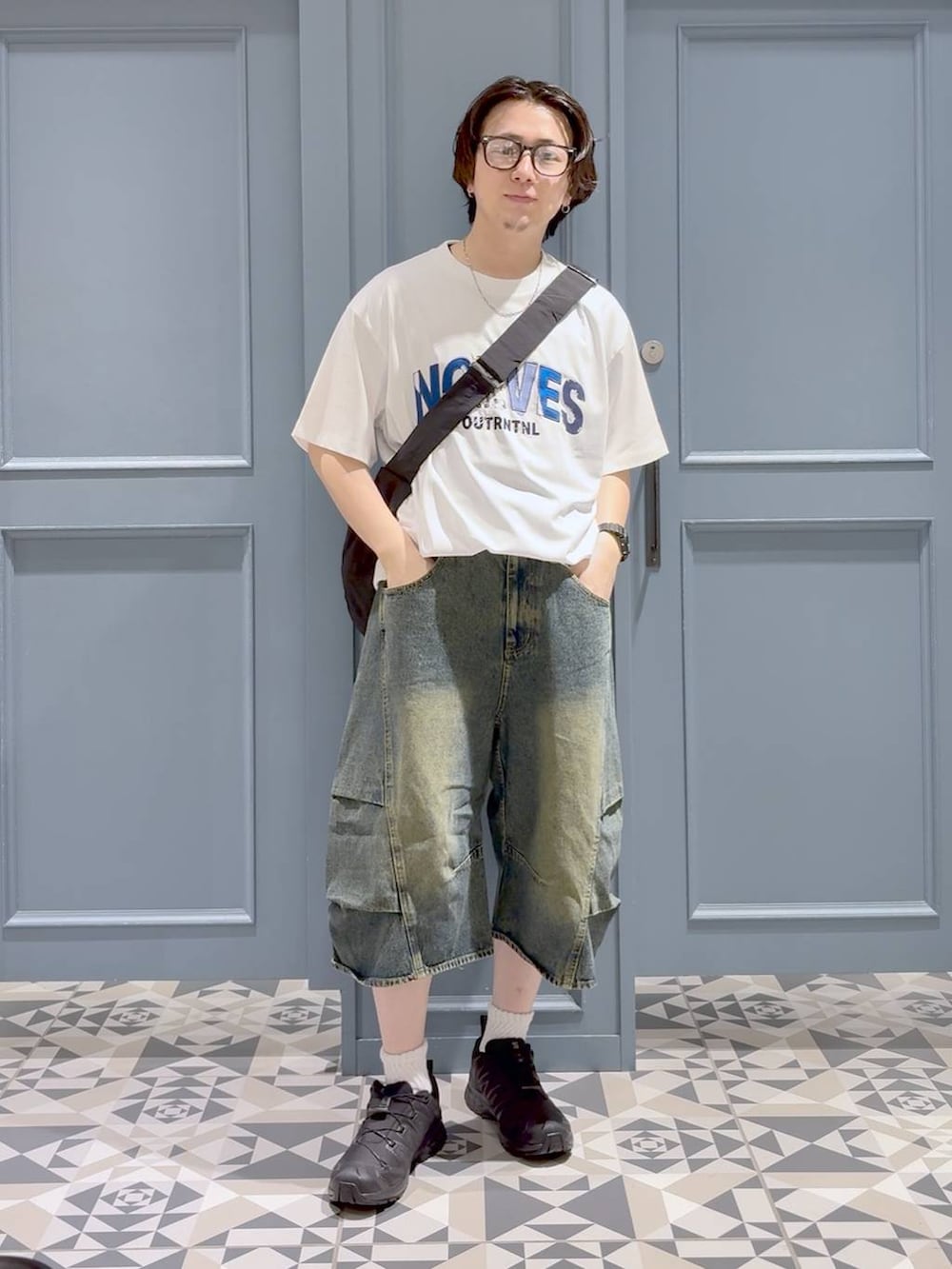 ブルー系のデニムパンツ、ブラック系のスニーカー、ブラック系のショルダーバッグを着用したメンズの夏コーディネートの4枚目の写真
