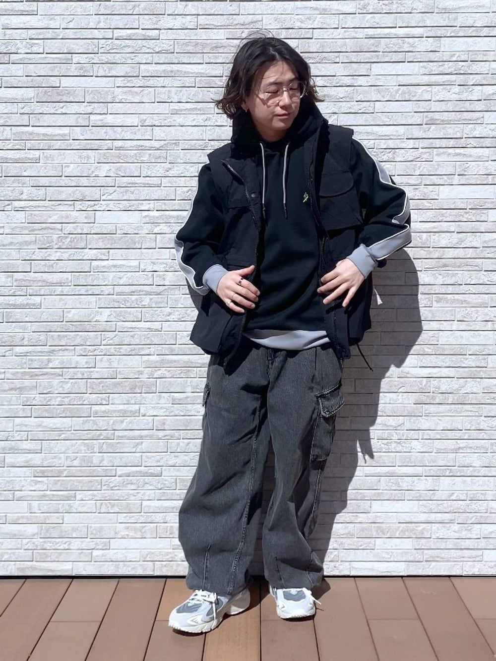グレー系のデニムパンツ、ブラック系のナイロンジャケット、ブラック系のパーカーを着用したメンズの春コーディネートの4枚目の写真