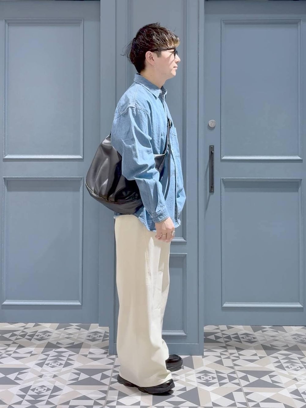 ブラック系のローファー、ブラック系のショルダーバッグ、ホワイト系のスラックスを着用したメンズの冬コーディネートの2枚目の写真