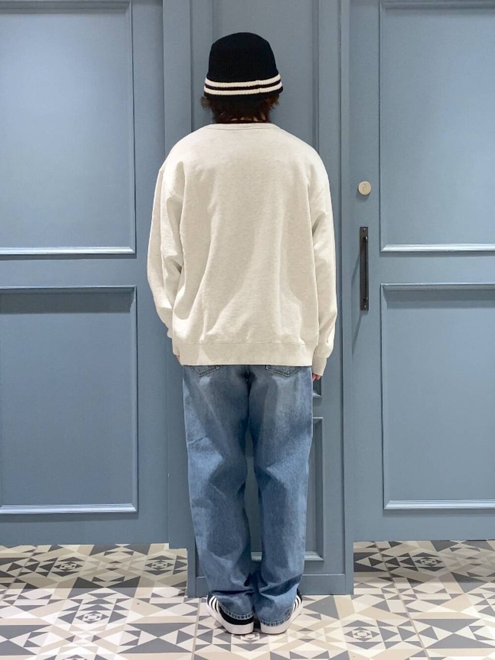 ブラック系のスニーカー、ホワイト系のスウェット、ブルー系のデニムパンツを着用したメンズの春コーディネートの3枚目の写真