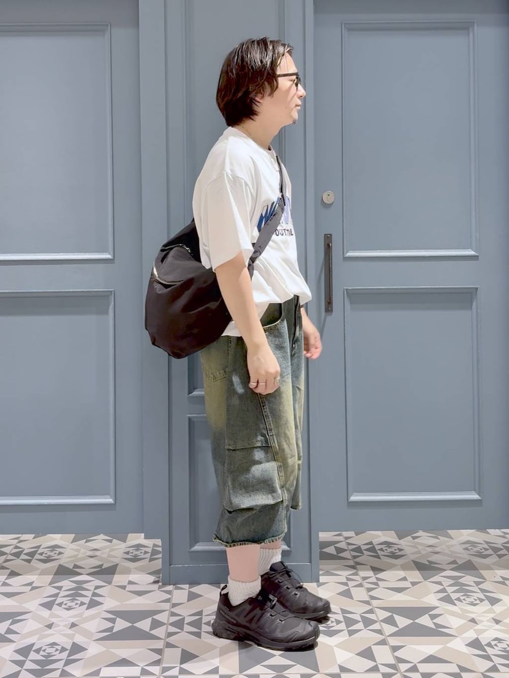 ブルー系のデニムパンツ、ブラック系のスニーカー、ブラック系のショルダーバッグを着用したメンズの夏コーディネートの2枚目の写真