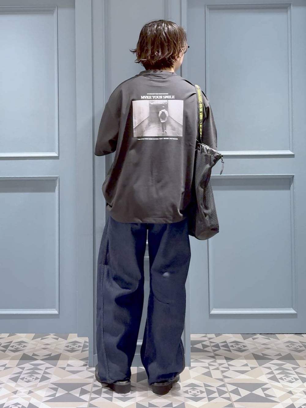 ブラック系のトートバッグ、ブラック系のサンダル、ブルー系のデニムパンツを着用したメンズの夏コーディネートの3枚目の写真