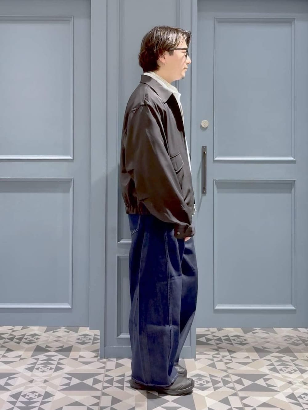 ブラック系のスニーカー、ブラック系のブルゾン、ホワイト系のシャツ/ブラウスを着用したメンズの春コーディネートの2枚目の写真