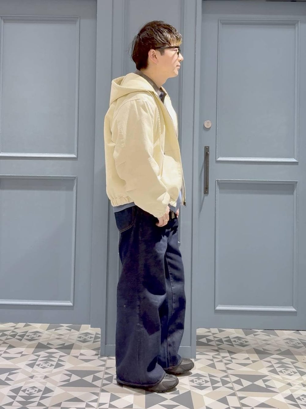 ブルー系のデニムパンツ、ホワイト系のブルゾン、ブルー系のニット/セーターを着用したメンズの冬コーディネートの2枚目の写真