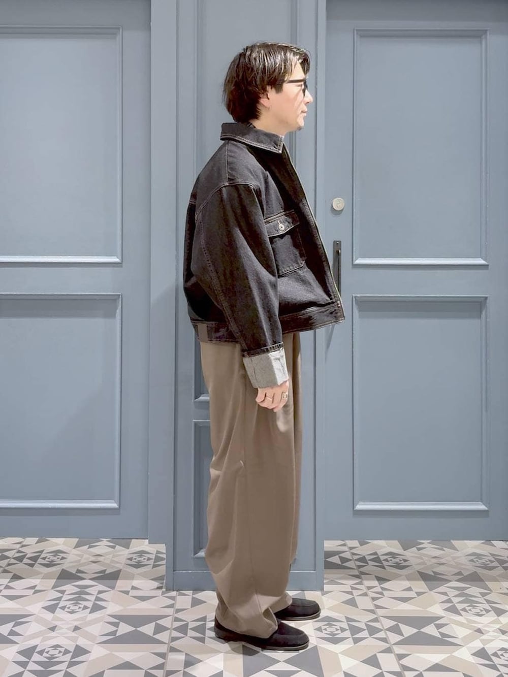 ブラック系のデニムジャケット、イエロー系のスラックス、ブラック系のブルゾンを着用したメンズの春コーディネートの2枚目の写真