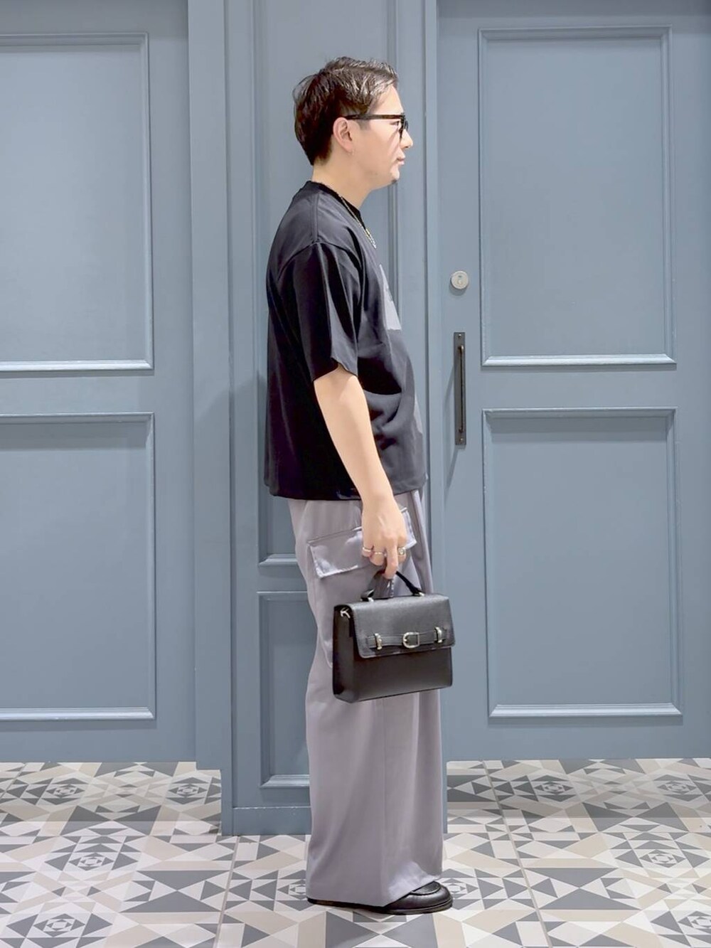 ブラック系のTシャツ/カットソー、ブラック系のローファー、ブラック系のショルダーバッグを着用したメンズの秋コーディネートの2枚目の写真