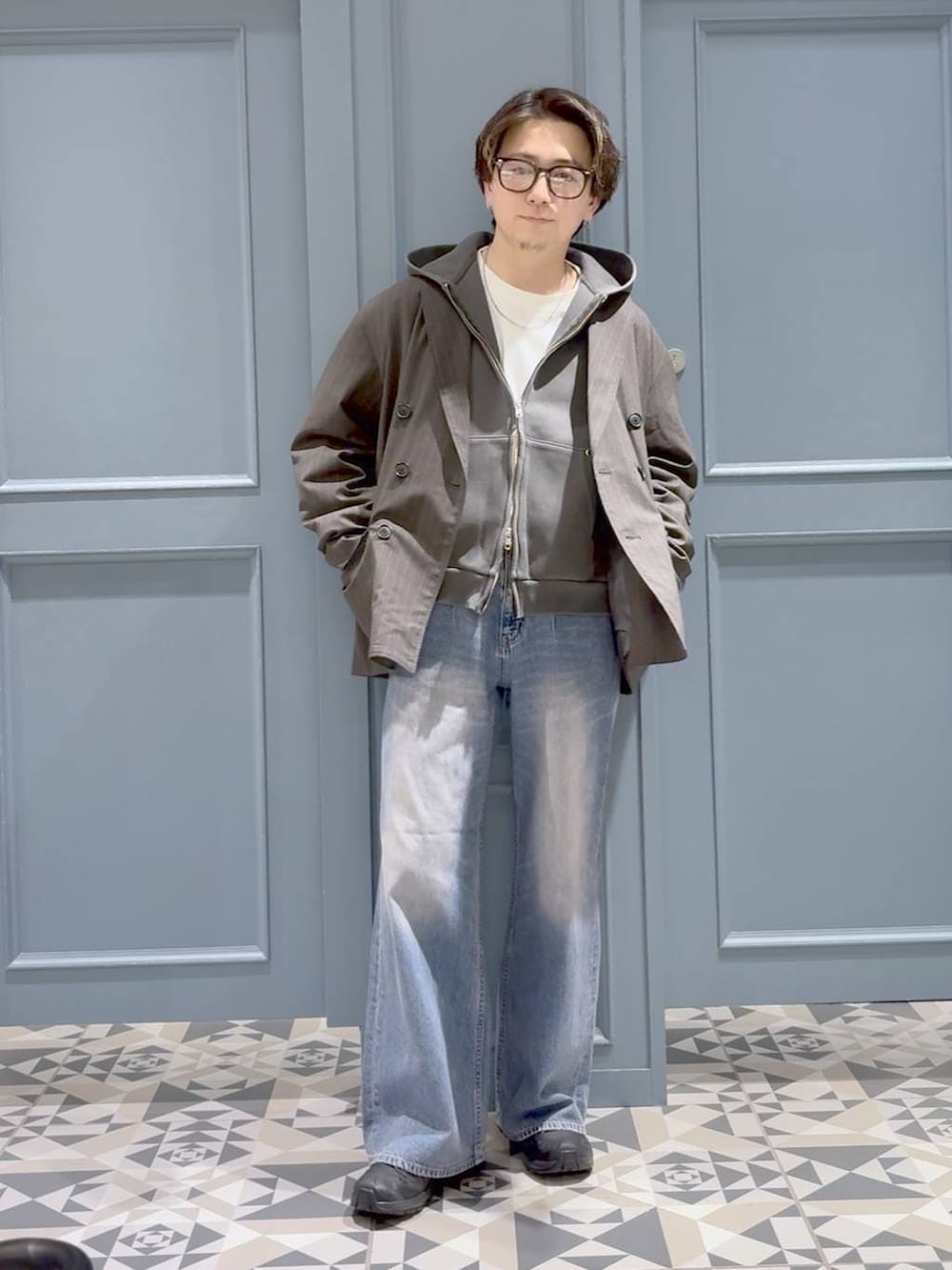 グレー系のテーラードジャケット、ブラック系のスニーカー、その他のパーカーを着用したメンズの春コーディネートの4枚目の写真