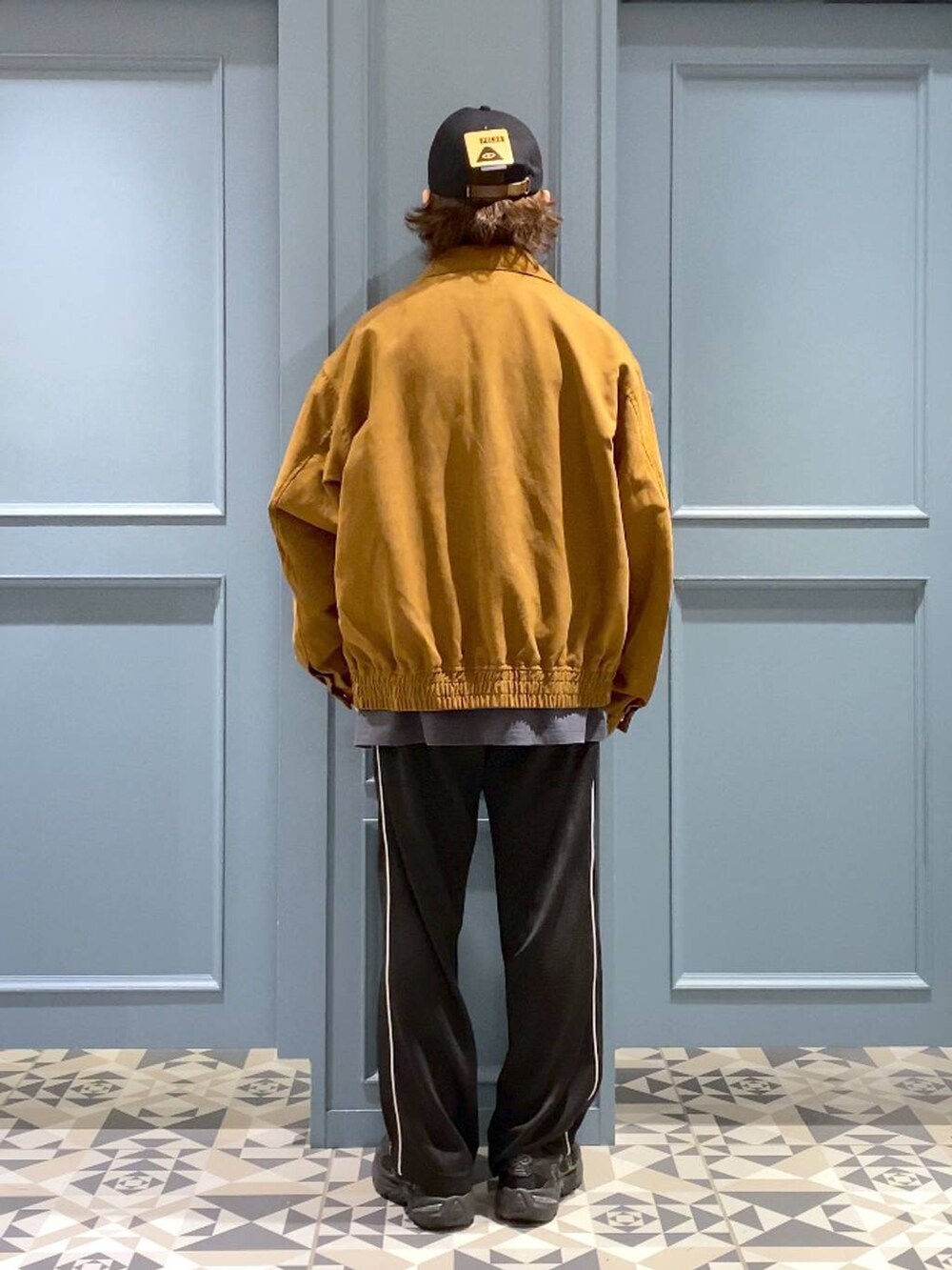 ブラック系のスニーカー、イエロー系のブルゾン、ブラック系のスウェットパンツを着用したメンズの秋コーディネートの3枚目の写真