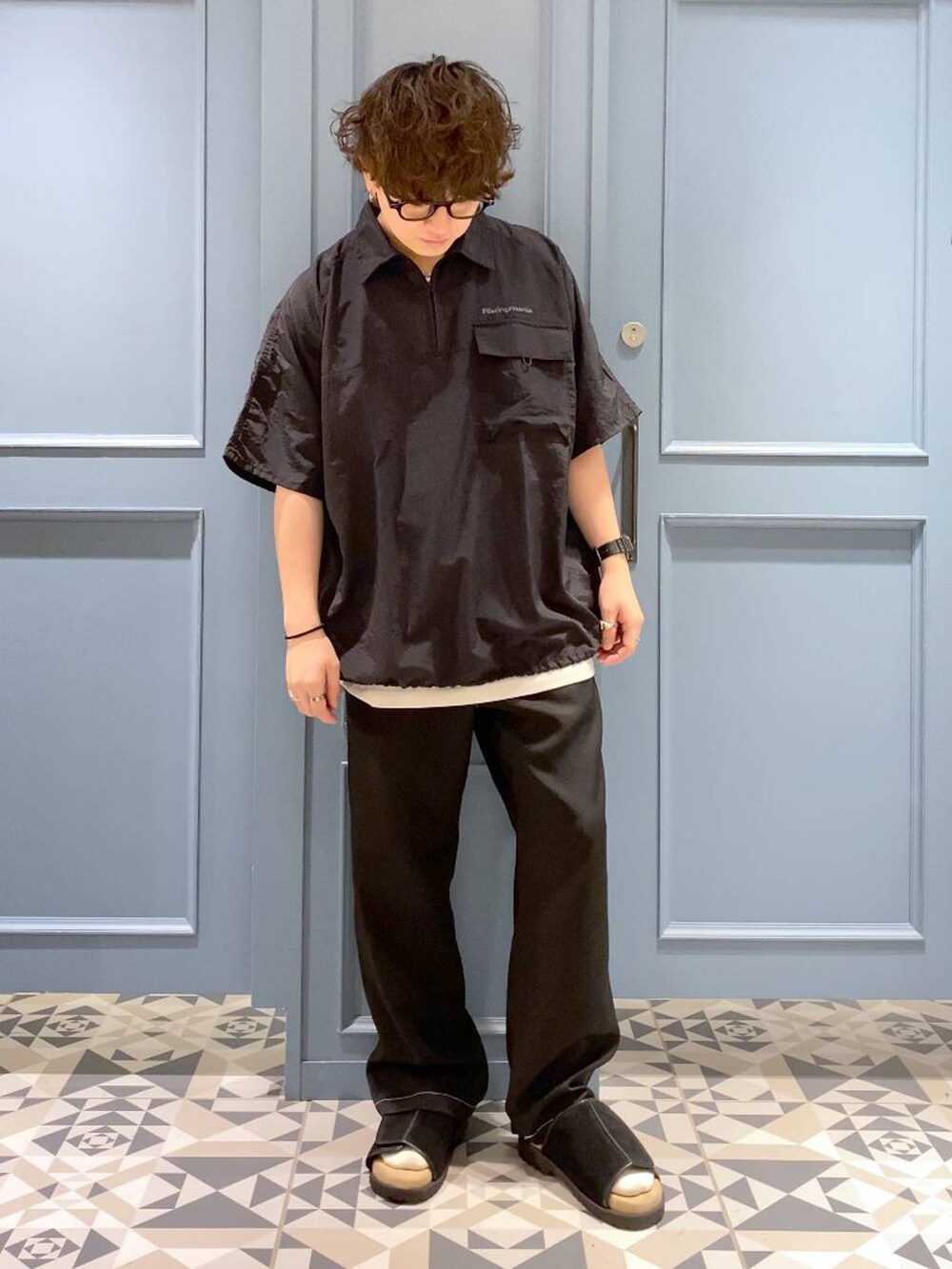 ブラック系のサンダル、ホワイト系のタンクトップ、ブラック系のスラックスを着用したメンズの夏コーディネートの4枚目の写真