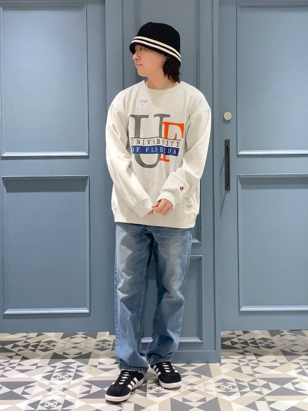 ブラック系のスニーカー、ホワイト系のスウェット、ブルー系のデニムパンツを着用したメンズの春コーディネートの4枚目の写真