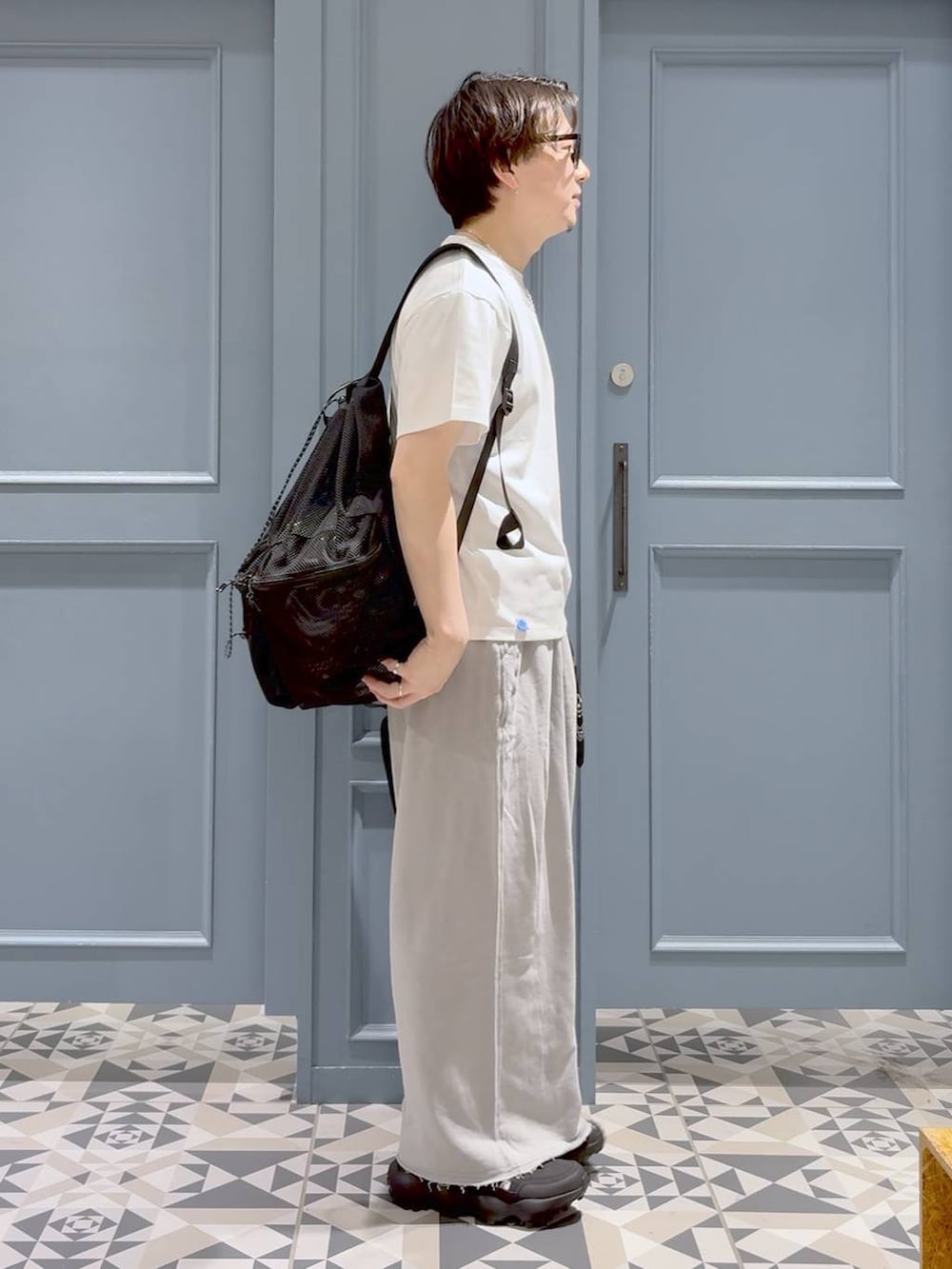ブラック系のサンダル、ホワイト系のTシャツ/カットソー、ブラック系のバックパック/リュックを着用したメンズの夏コーディネートの2枚目の写真
