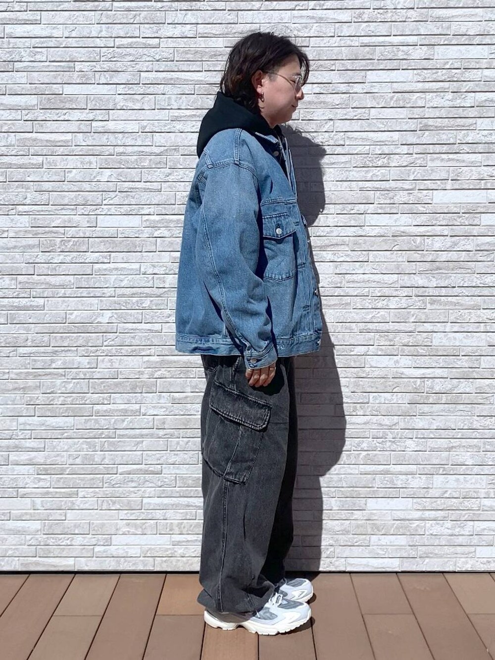 グレー系のデニムパンツ、ブルー系のデニムジャケット、ブラック系のパーカーを着用したメンズの春コーディネートの2枚目の写真