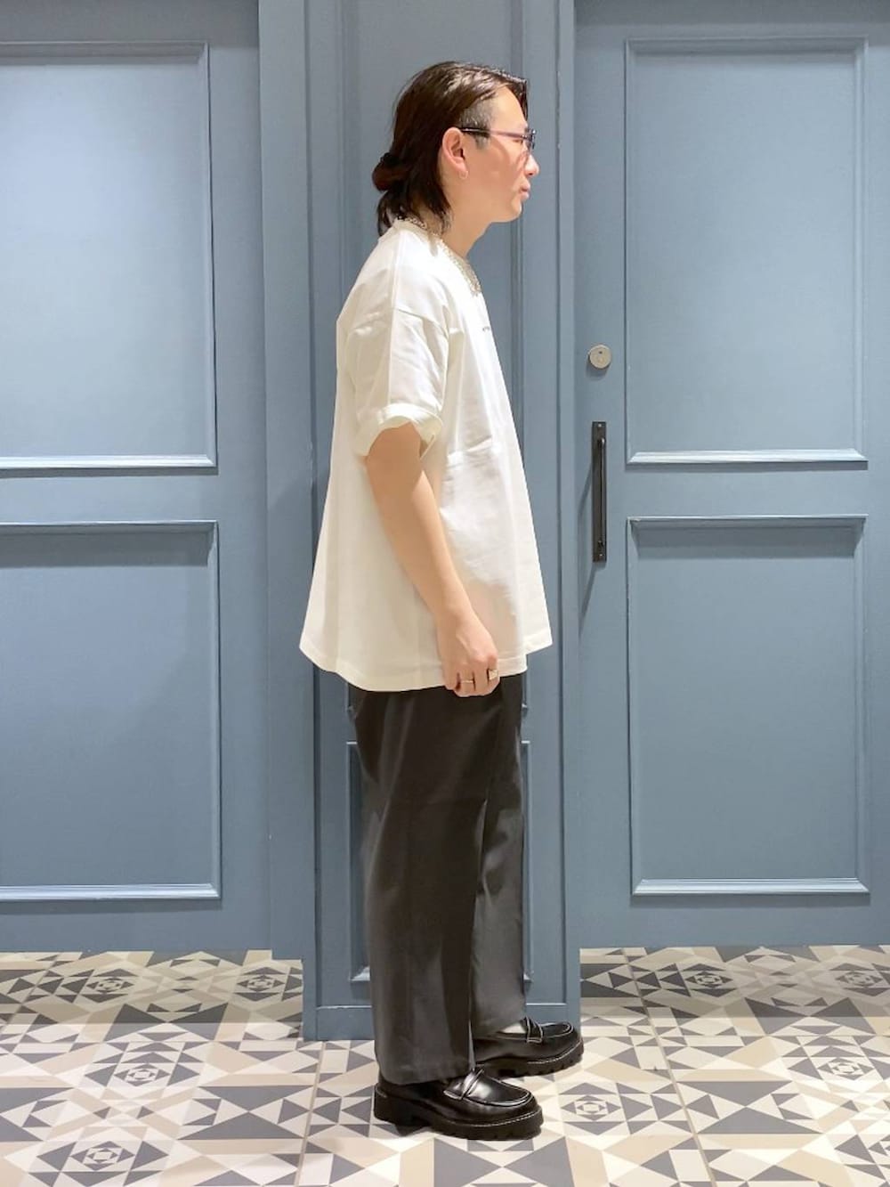 グレー系のスラックス、ブラック系のドレスシューズ、ホワイト系のTシャツ/カットソーを着用したメンズの春コーディネートの2枚目の写真