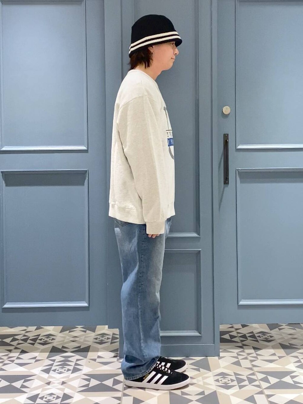 ブラック系のスニーカー、ホワイト系のスウェット、ブルー系のデニムパンツを着用したメンズの春コーディネートの2枚目の写真