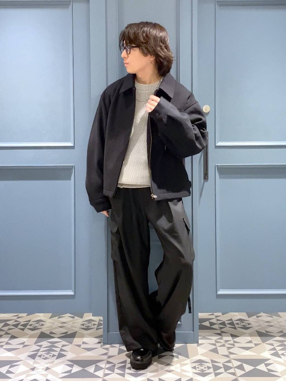 ブラック系のブルゾン、ブラック系のドレスシューズ、ブルー系のニット/セーターを着用したメンズの冬コーディネートの4枚目の写真