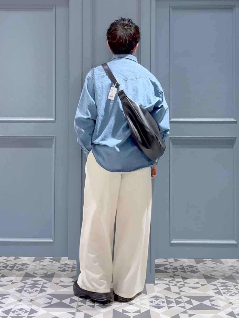 ブラック系のローファー、ブラック系のショルダーバッグ、ホワイト系のスラックスを着用したメンズの冬コーディネートの3枚目の写真