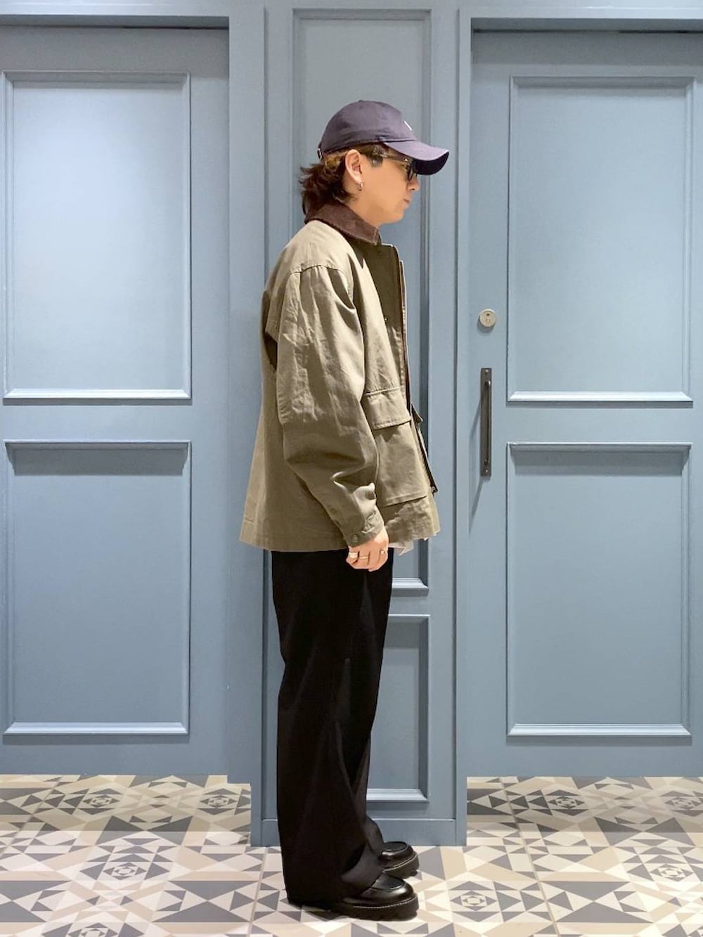 ブラック系のスラックス、グリーン系のブルゾン、ブラック系のドレスシューズを着用したメンズの秋コーディネートの2枚目の写真