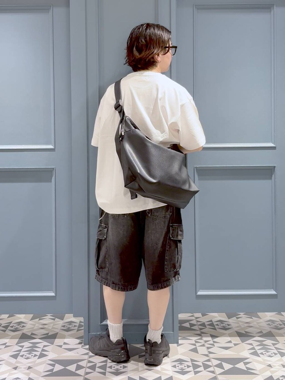 ブラック系のスニーカー、ブラック系のショルダーバッグ、ブラック系のカーゴパンツを着用したメンズの夏コーディネートの3枚目の写真