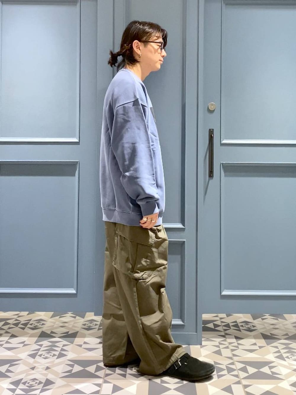 グリーン系のカーゴパンツ、ブルー系のスウェット、ブラック系のサングラスを着用したメンズの冬コーディネートの2枚目の写真