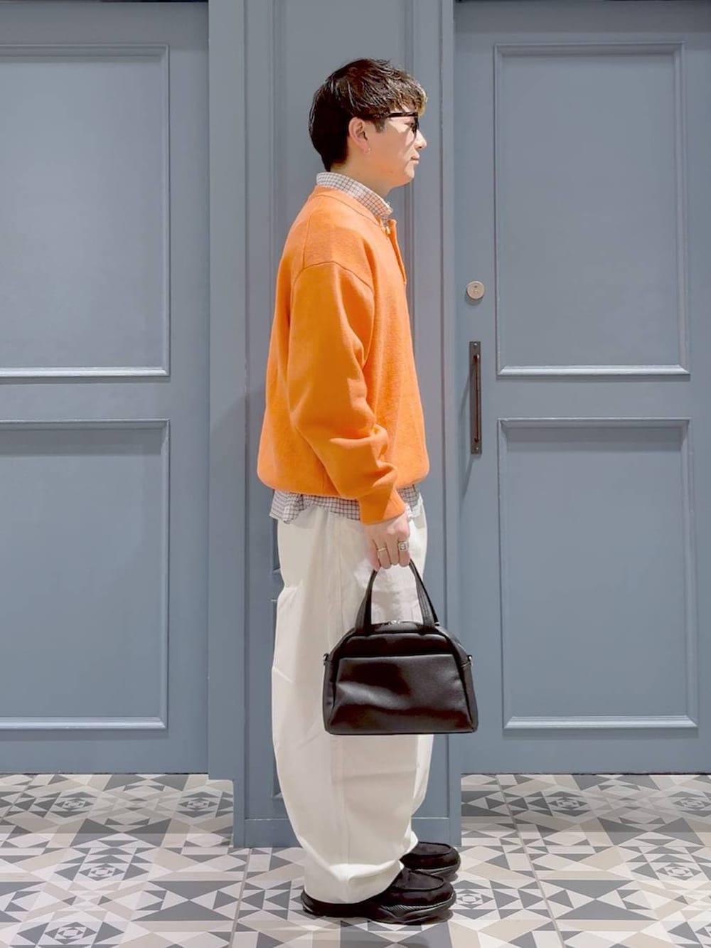 ブラック系のローファー、オレンジ系のニット/セーター、ホワイト系のシャツ/ブラウスを着用したメンズの冬コーディネートの2枚目の写真