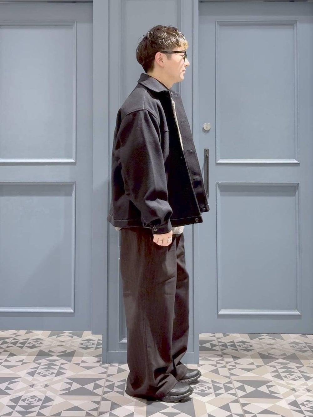 ブラウン系のスラックス、ブラック系のブルゾン、ブラック系のシャツ/ブラウスを着用したメンズの冬コーディネートの2枚目の写真