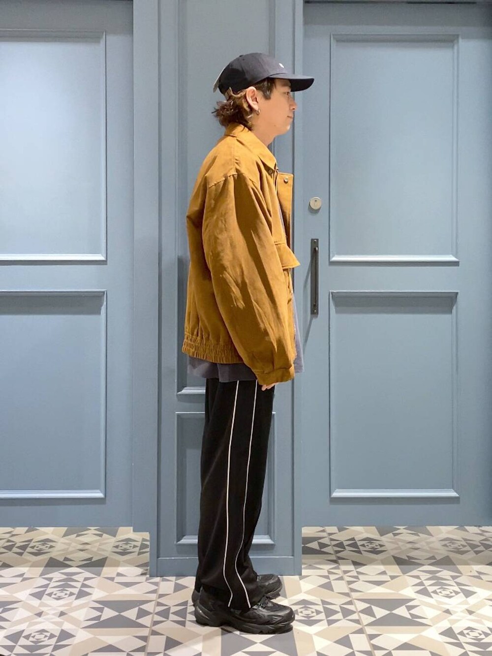 ブラック系のスニーカー、イエロー系のブルゾン、ブラック系のスウェットパンツを着用したメンズの秋コーディネートの2枚目の写真