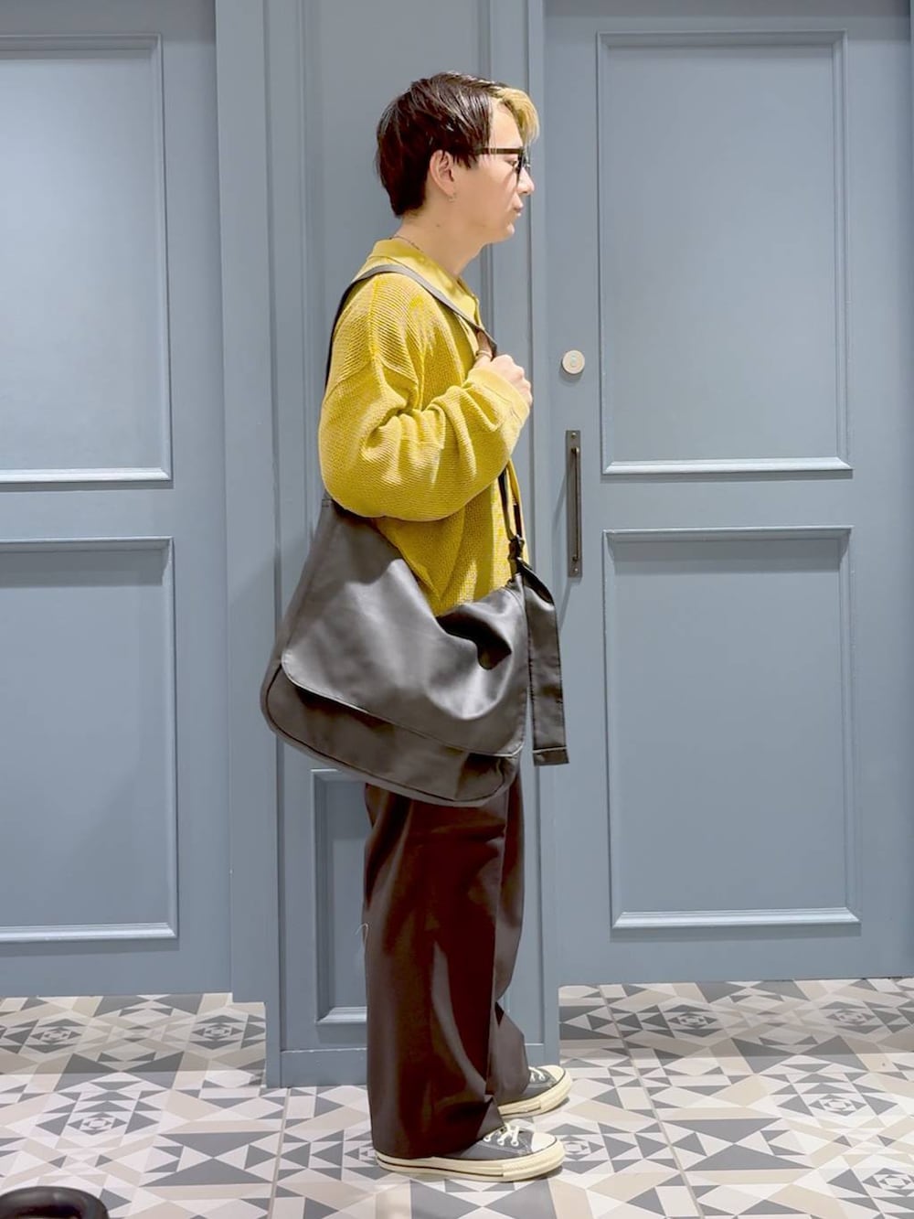 ブラック系のショルダーバッグ、ブラック系のスラックス、イエロー系のカーディガン/ボレロを着用したメンズの秋コーディネートの2枚目の写真