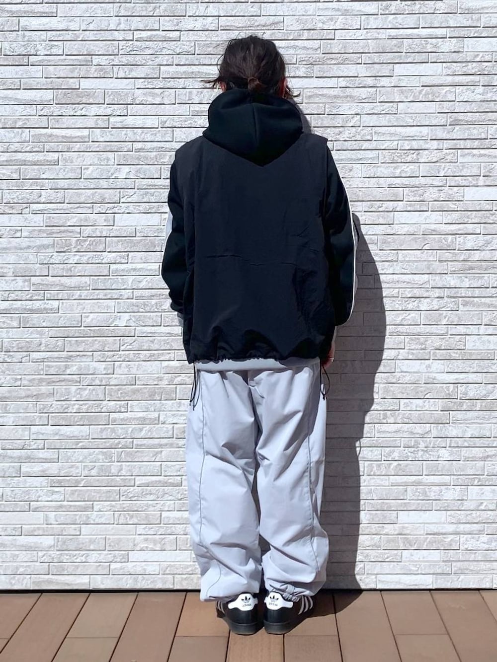 ブラック系のパーカー、ブラック系のナイロンジャケット、ホワイト系のスウェットパンツを着用したメンズの春コーディネートの3枚目の写真