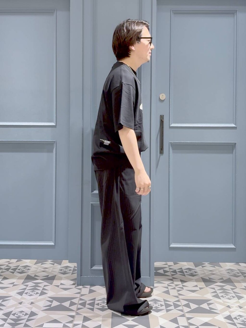 ブラック系のスラックス、ブラック系のTシャツ/カットソー、その他のネックレスを着用したメンズの夏コーディネートの2枚目の写真