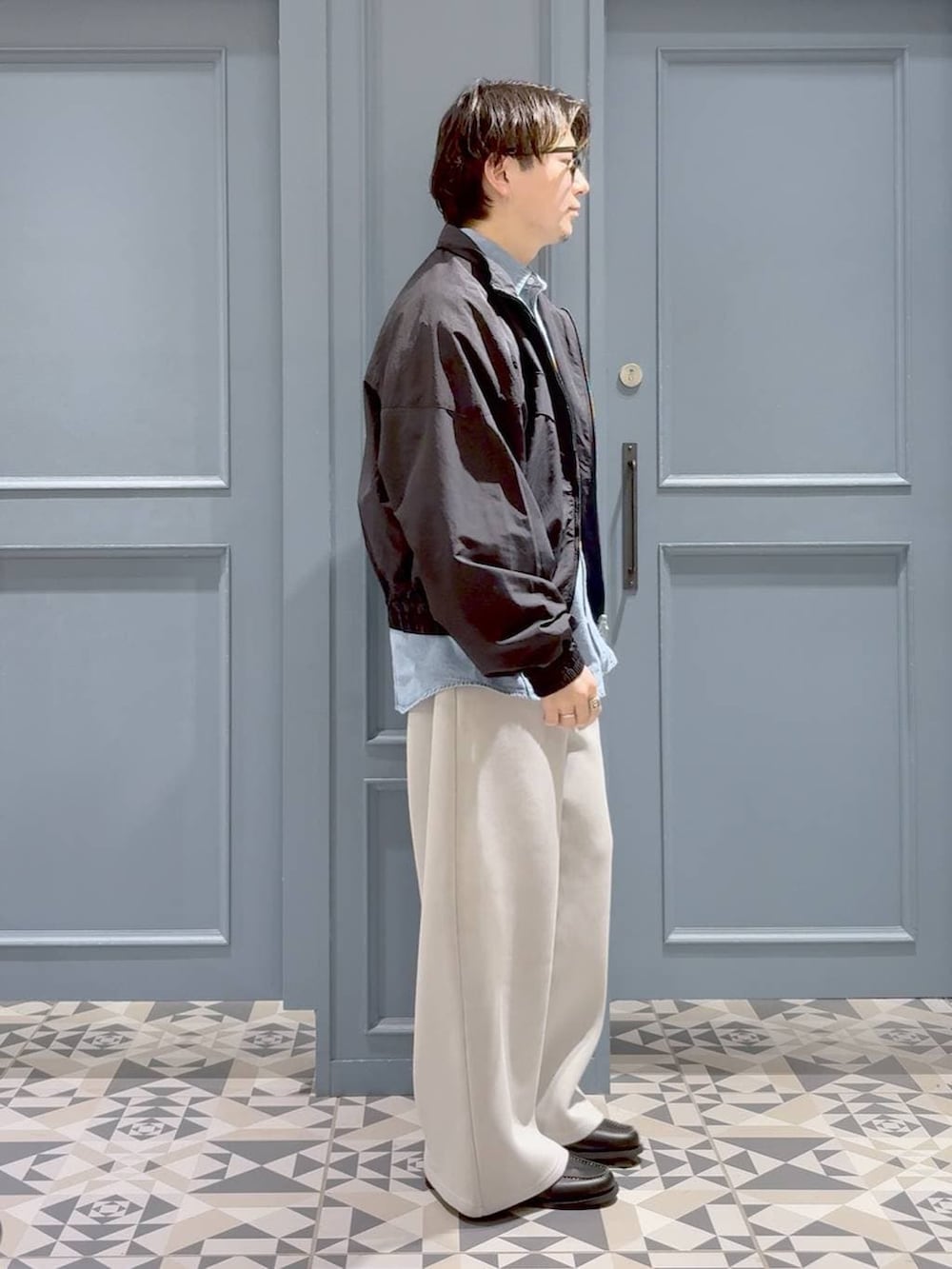 ブラック系のモカシン/デッキシューズ、ブラック系のナイロンジャケット、グレー系のその他パンツを着用したメンズの春コーディネートの2枚目の写真