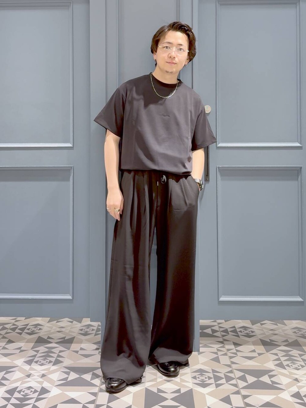 ブラック系のローファー、グレー系のスラックス、ブラック系のTシャツ/カットソーを着用したメンズの夏コーディネートの4枚目の写真