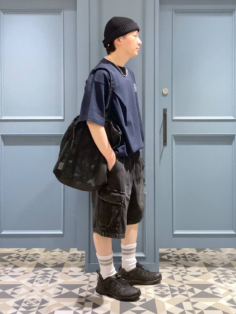 ブラック系のスニーカー、グレー系のカーゴパンツ、ブラック系のトートバッグを着用したメンズの春コーディネートの2枚目の写真