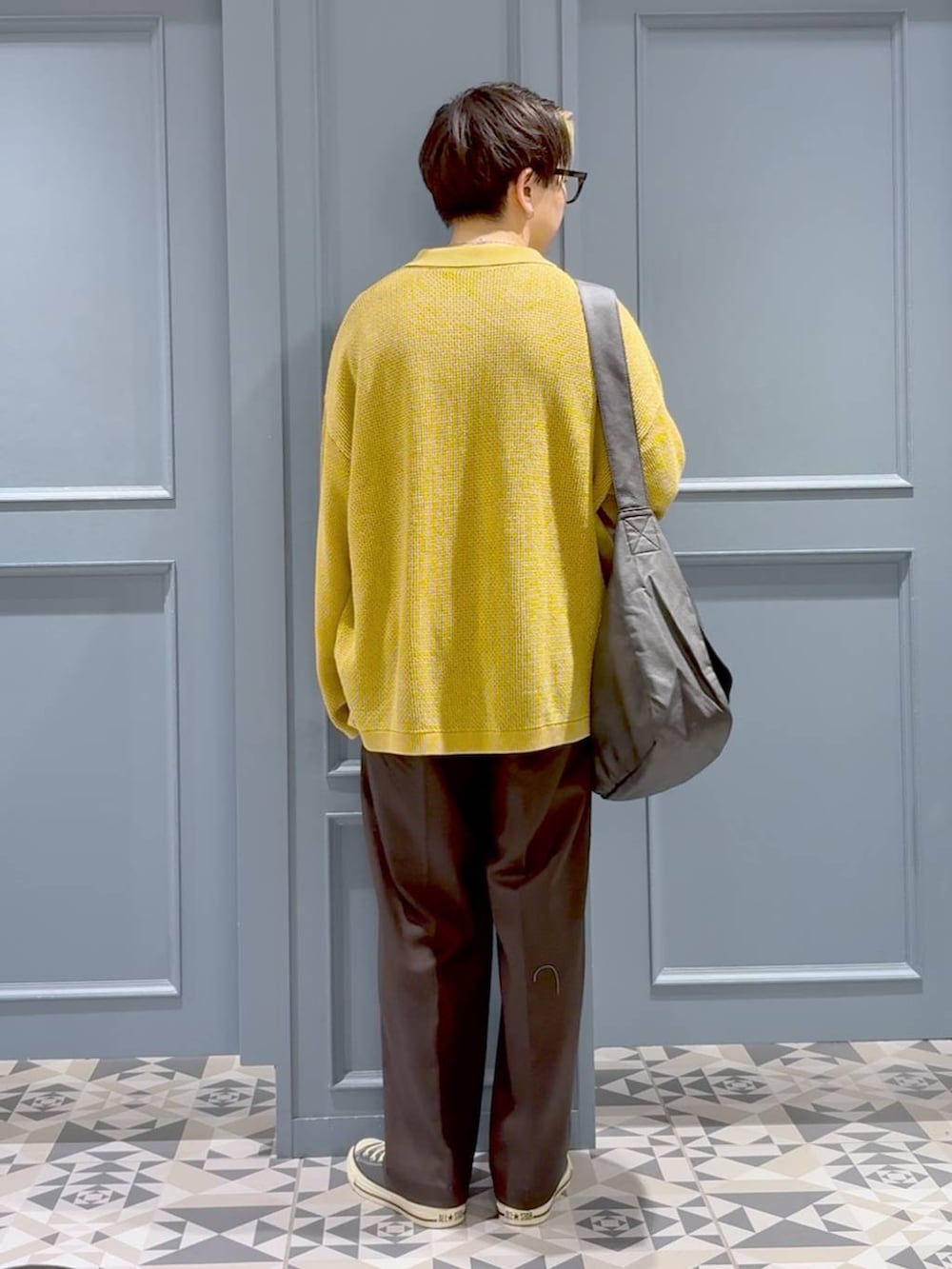 ブラック系のショルダーバッグ、ブラック系のスラックス、イエロー系のカーディガン/ボレロを着用したメンズの秋コーディネートの3枚目の写真